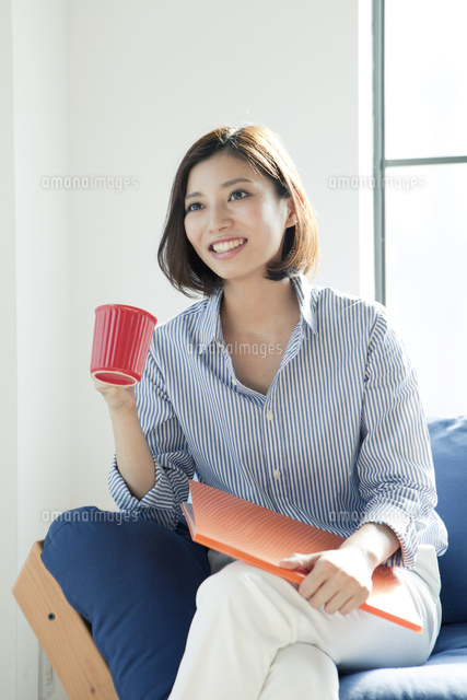 ソファーでコップを持つ20代女性
(c)absodels RF