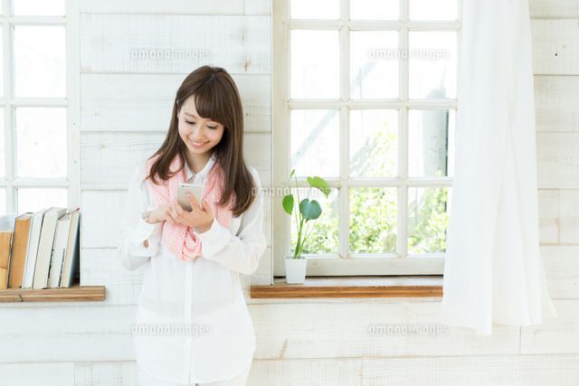 部屋で携帯電話を使う若い女性
(c)forty-one/amanaimagesRF