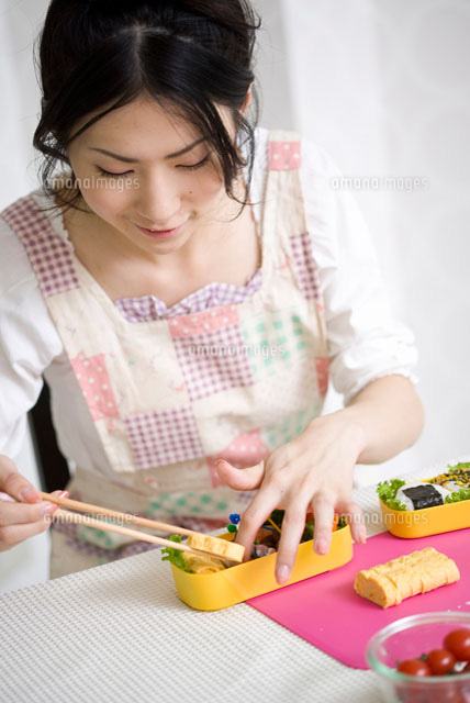お弁当箱におかずを詰める女性
(c)didi
