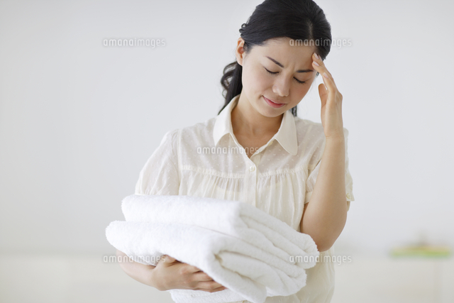 家事の途中に頭痛で苦しむ若い女性
(c)mon printemps