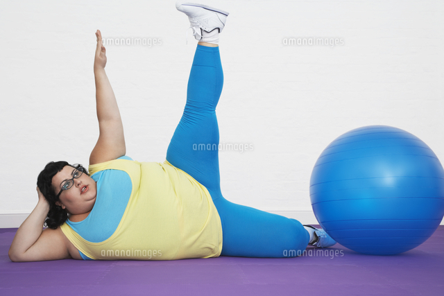 Overweight Woman lying by exercise ball stretching arm and l
(c)moodboard