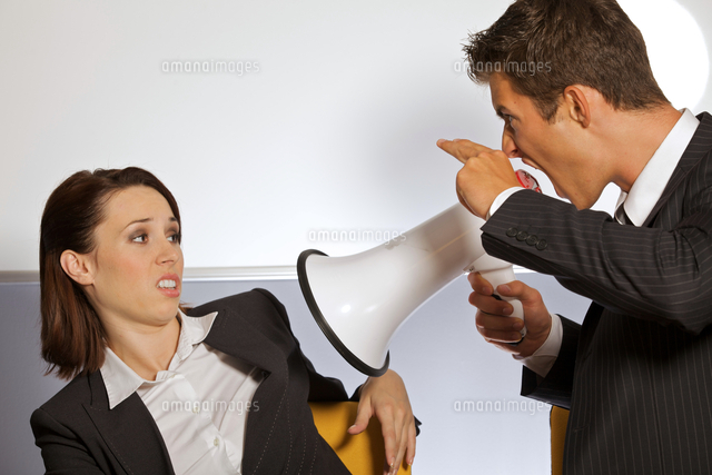 Businessman shouting at businesswoman through megaphone and gesturing gun sign
(c)moodboard