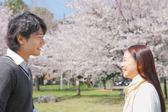 桜の咲く公園で向かい合う笑顔の男女
(c)iconics