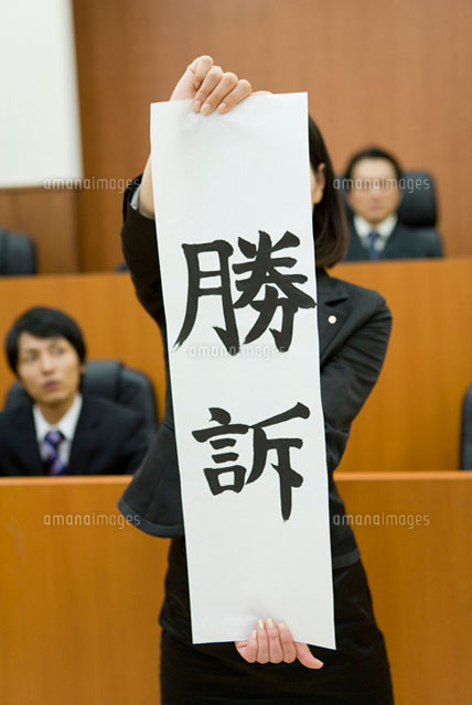 勝訴の紙を持った若い女性
(c)DAJ