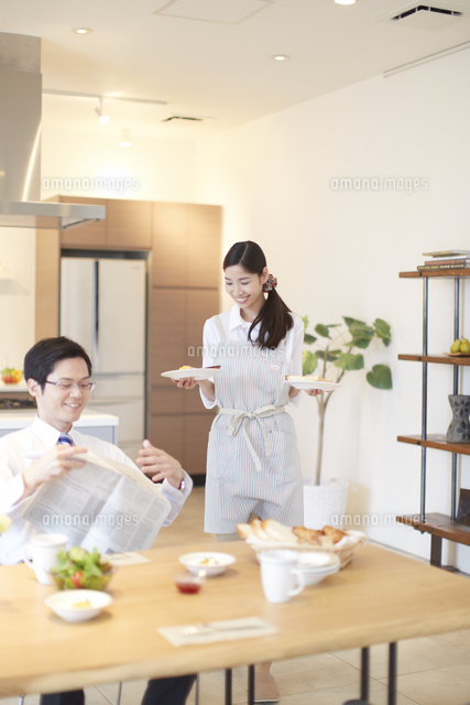 出勤前の朝食を運ぶ奥さんと新聞をたたむ夫
(c)apjt