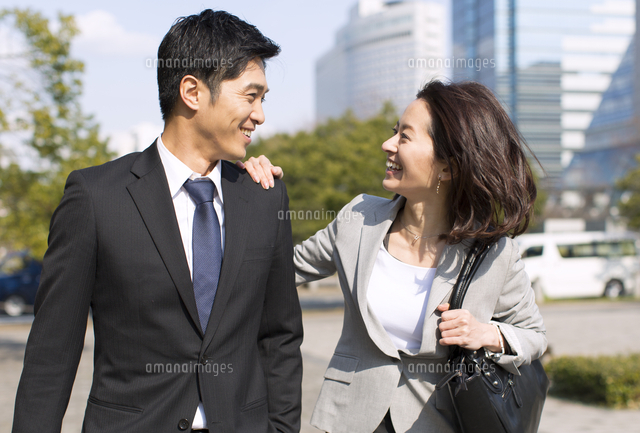 肩に手をかけて挨拶をするビジネス男女
(c)apjt