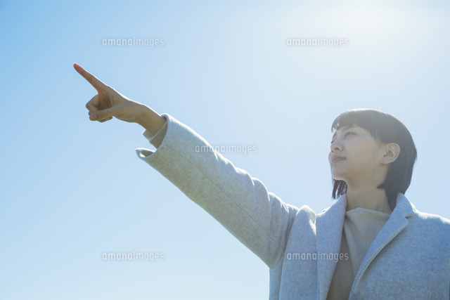 青空の下指差しをする20代女性
(c)absodels RF