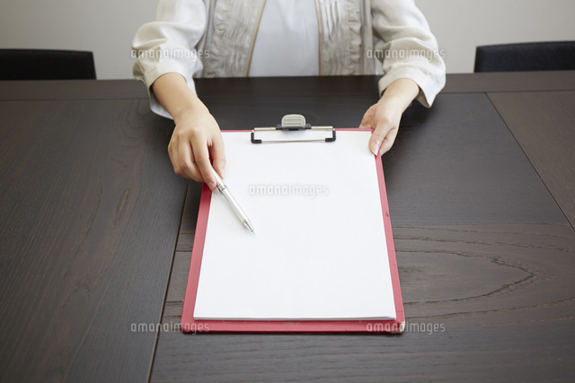 デスクの上でこちらに向けて書類を見せる女性の手元
(c)IDC/a.collectionRF