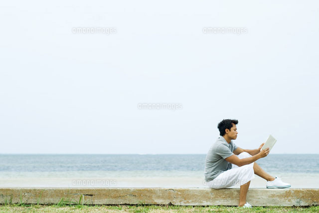 Man sitting on low wall, reading book
(c)Eric Audras/Photo Alto
