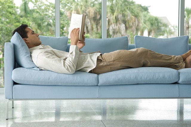 man lying on couch reading book
(c)Eric Audras/Photo Alto