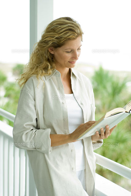 Woman standing on porch reading book
(c)Eric Audras/Photo Alto