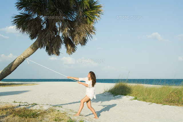 Woman pulling palm tree with rope
(c)Milena Boniek/Photo Alto
