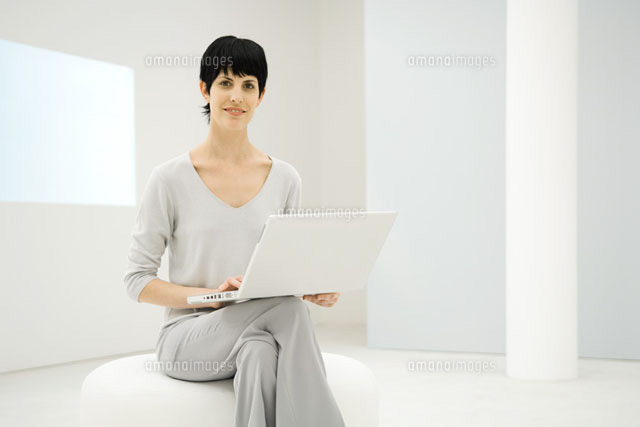 Woman sitting, holding laptop computer
(c)Eric Audras/Photo Alto