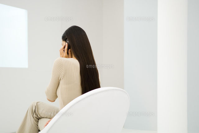 Woman sitting in chair, using cell phone
(c)Eric Audras/Photo Alto