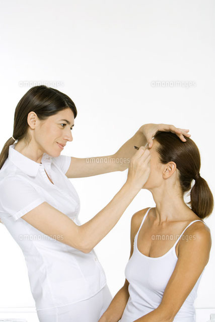 Beautician carefully plucking a woman’s eyebrows, smiling
(c)Alix Minde/PhotoAlto