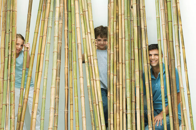 Father and two children peeking through bamboo at camera
(c)Odilon Dimier/PhotoAlto