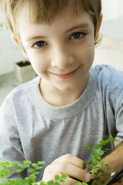 Boy touching plant, smiling at camera, close-up
(c)Odilon Dimier/PhotoAlto
