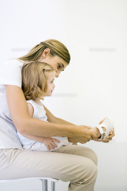 Mother helping her young daughter put her shoe on
(c)Sigrid Olsson/PhotoAlto