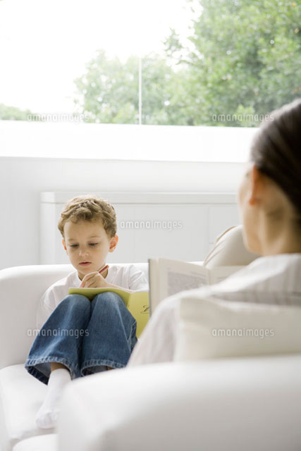 Boy sitting on couch, writing in book, woman reading book
(c)Sigrid Olsson/PhotoAlto