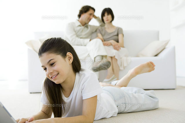 Girl lying on stomach on the floor,parents sitting on couch
(c)Sigrid Olsson/PhotoAlto