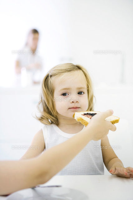 Girl sitting at table, being fed a piece of bread with jam
(c)Sigrid Olsson/PhotoAlto