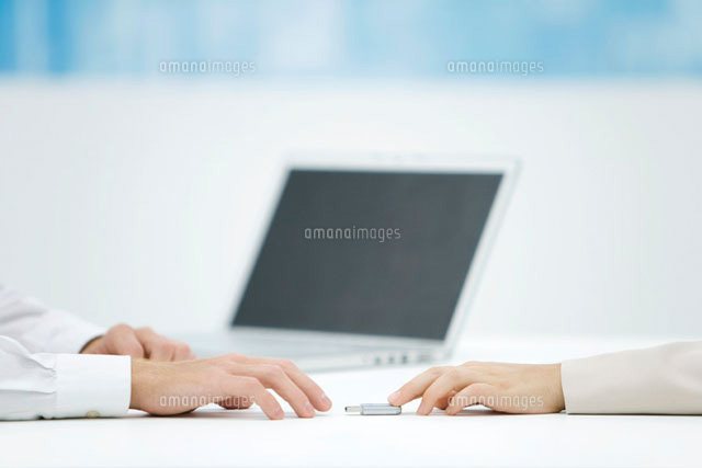Hand pushing a flash drive across desk
(c)Alix Minde/PhotoAlto