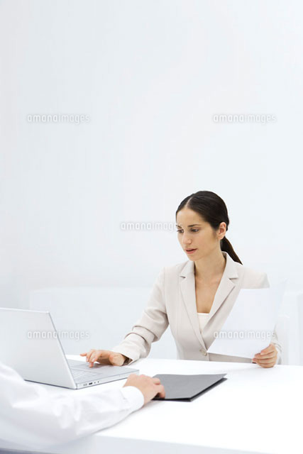 Woman using laptop while holding a document of arm
(c)Alix Minde/PhotoAlto