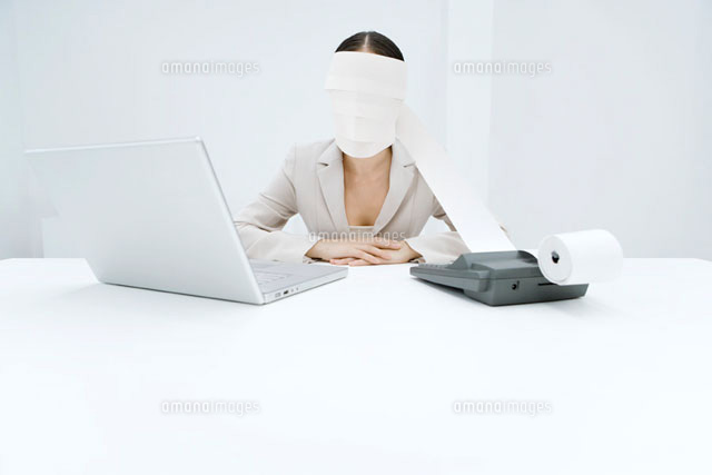 Woman sitting at desk with adding machine and laptop
(c)Alix Minde/PhotoAlto