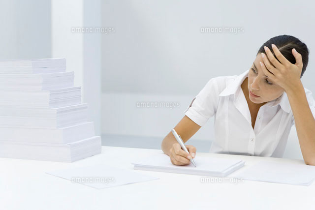 Woman holding her forehead, writing on blank sheet of paper
(c)Alix Minde/PhotoAlto