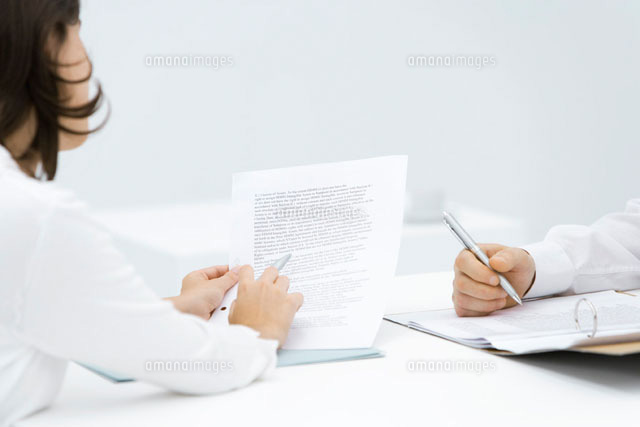 Woman scrutinizing contract, man editing document in binder
(c)Alix Minde/PhotoAlto