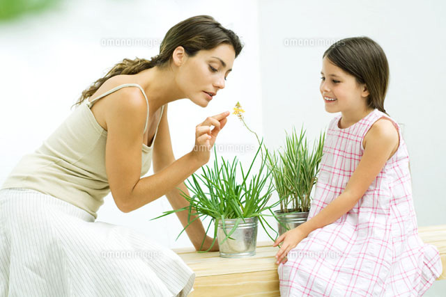 Woman smelling flower sprig while daughter watches
(c)Eric Audras/PhotoAlto