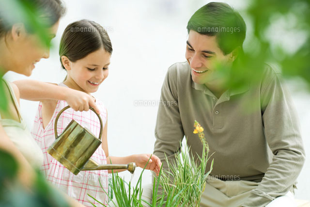 Girl watering plants, parents watching, all smiling
(c)Eric Audras/PhotoAlto