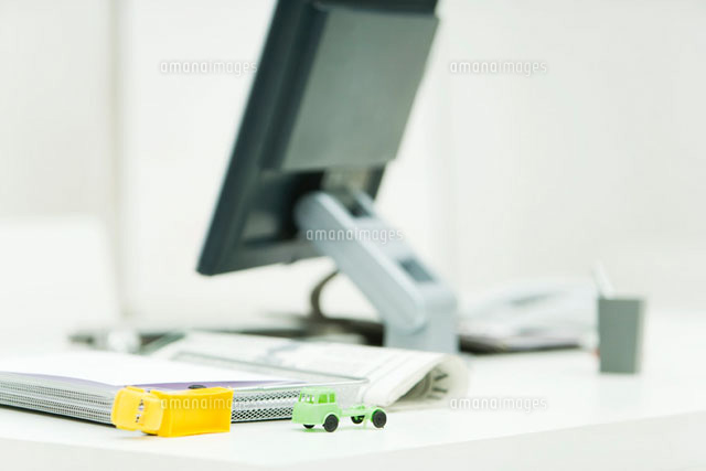 Toy trucks sitting on professional desk in office
(c)Alix Minde/PhotoAlto
