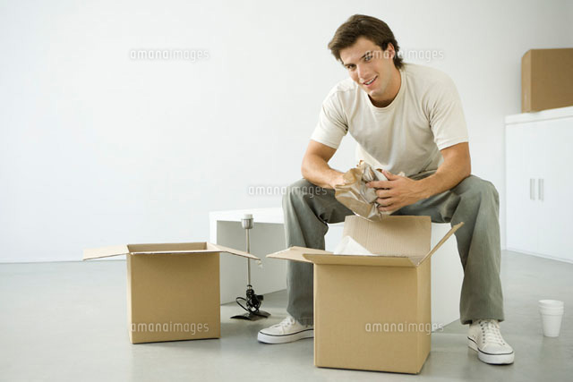Man unpacking boxes, sitting on bench, smiling at camera
(c)Alix Minde/PhotoAlto