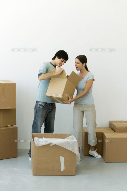 Couple unpacking, man showing contents of one box
(c)Alix Minde/PhotoAlto