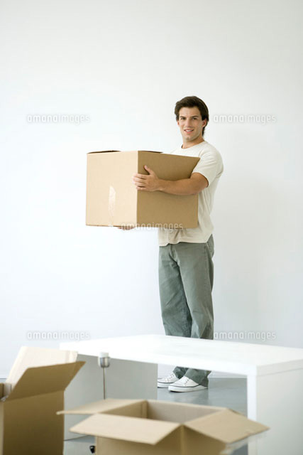 Man holding cardboard box, smiling at camera
(c)Alix Minde/PhotoAlto