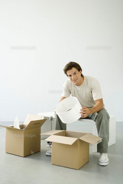 Man unpacking boxes, holding lampshade, smiling at camera
(c)Alix Minde/PhotoAlto