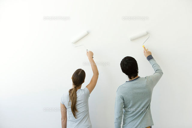Couple using paint rollers on wall, rear view
(c)Alix Minde/PhotoAlto