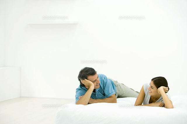 Couple lying on bed, smiling at each other
(c)Alix Minde/PhotoAlto