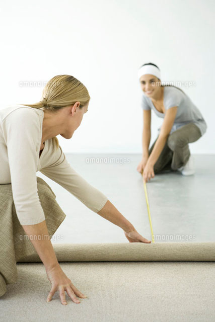 Mother and daughter installing carpet together
(c)Alix Minde/PhotoAlto