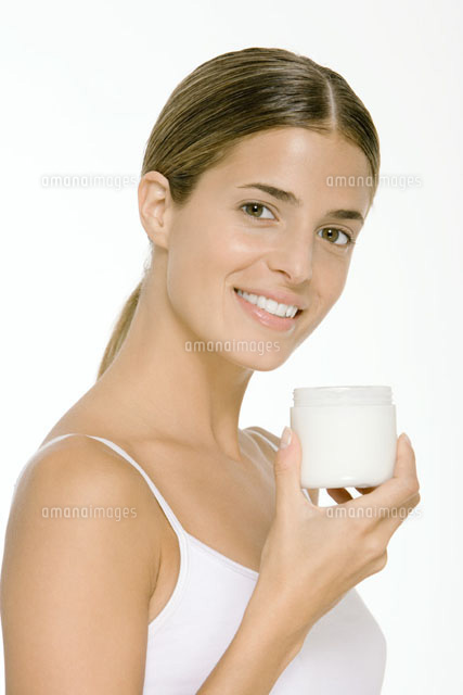 Woman holding up jar of skin cream,smiling at camera
(c)Alix Minde/PhotoAlto