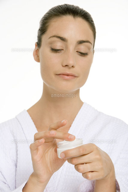 Woman in bathrobe dipping finger into jar of skin cream
(c)Alix Minde/PhotoAlto