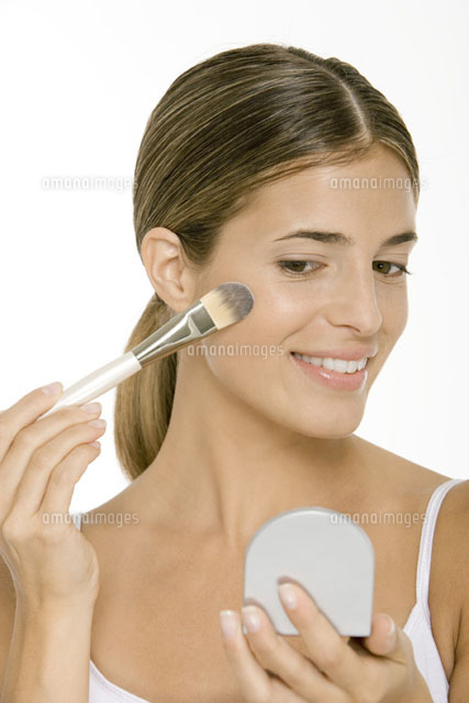Woman applying blush,looking in hand mirror
(c)Alix Minde/PhotoAlto