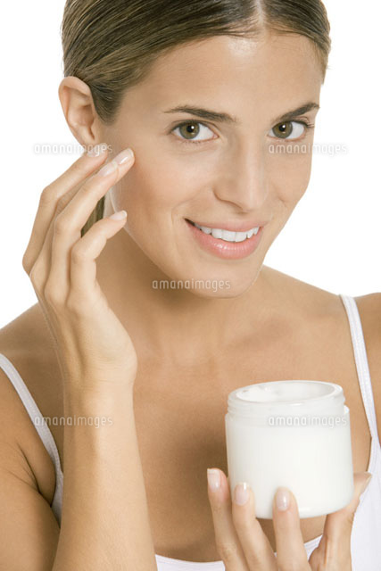 Woman applying moisturizer to face,smiling at camera
(c)Alix Minde/PhotoAlto