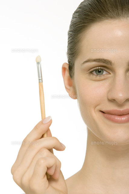 Woman holding up make-up brush
(c)Alix Minde/PhotoAlto