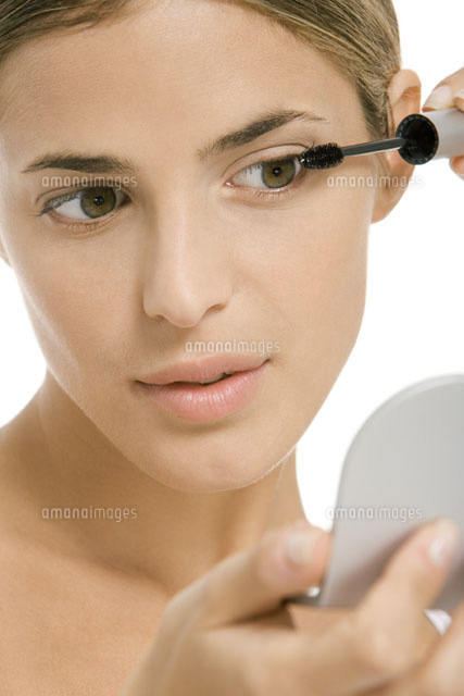 Woman putting on mascara,looking in hand mirror,close-up
(c)Alix Minde/PhotoAlto
