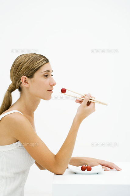 Young woman sitting,eating grape with chopsticks
(c)Laurence Mouton/PhotoAlto