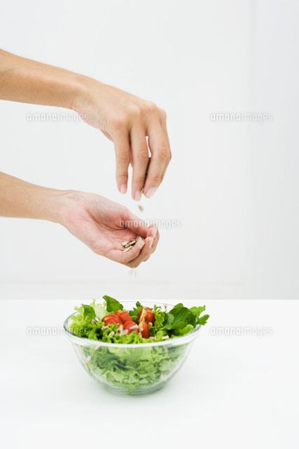 Woman sprinkling sunflower seeds on salad
(c)Laurence Mouton/PhotoAlto