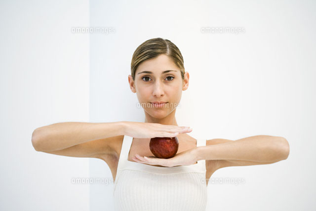 Woman balancing apple between hands,smiling at camera
(c)Laurence Mouton/PhotoAlto
