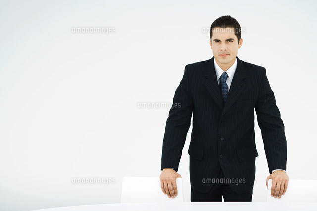 Businessman leaning on backs of chairs,looking at camera
(c)Frederic Cirou/PhotoAlto